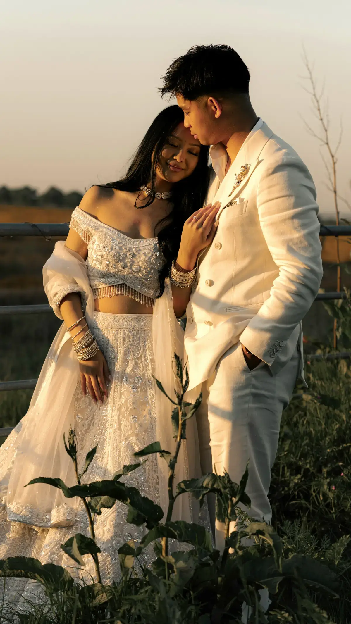 The couple in white wedding attire embracing at sunset
