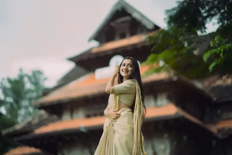 A woman in a pale yellow dress in front of a traditional temple-style building